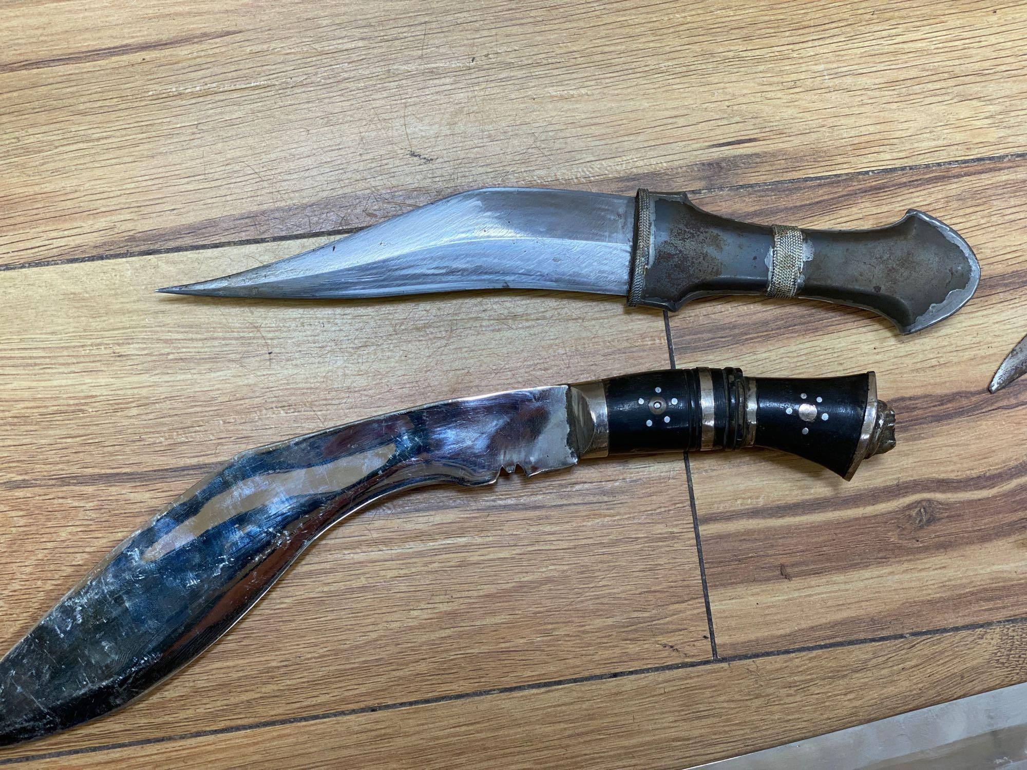 Five various weapons including a Kukri, a carved bone handled dagger with brass sun, moon and stars sheath and an El Salvador machete